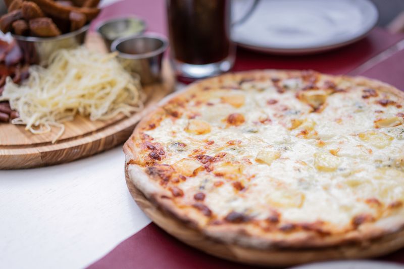 Apache Pizza special sauce being poured onto pizza base